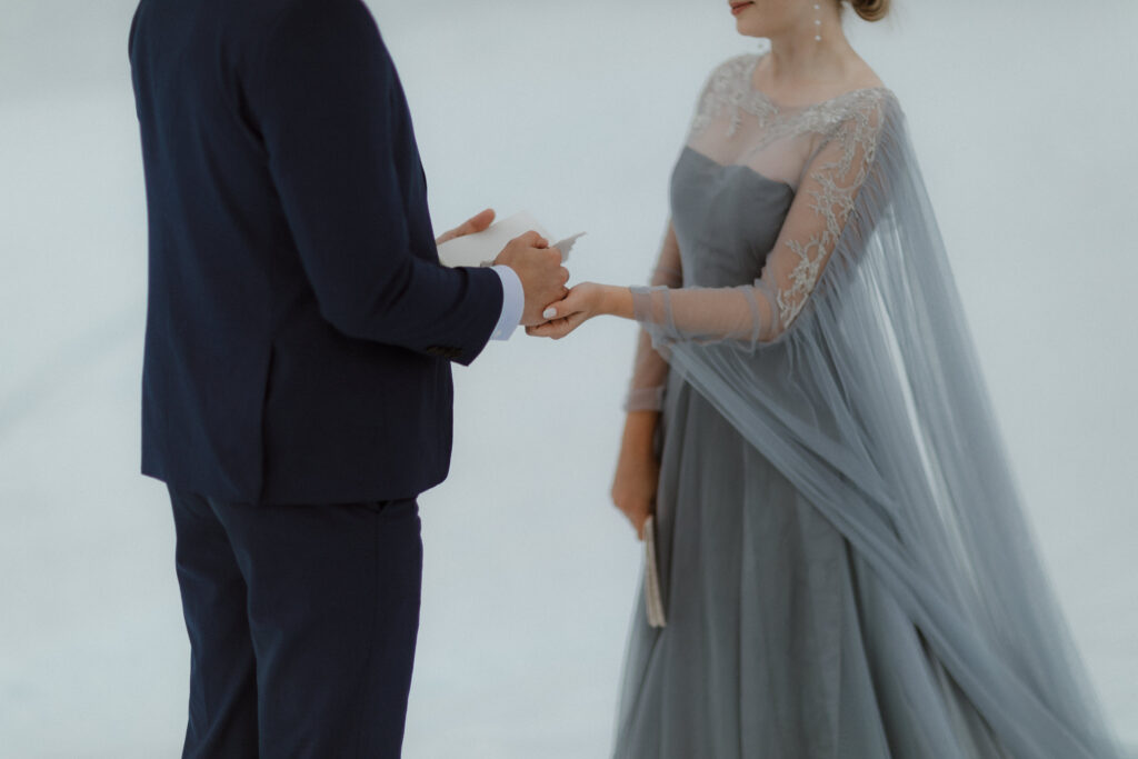 A bride in a blue wedding dress and a groom in a navy suit exchange vows on Matanuska Glacier in Sutton Alaska