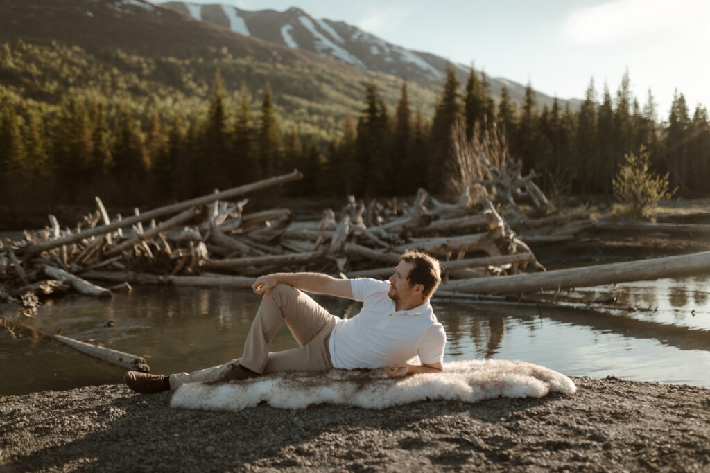 Man with mountains behind him during golden hour posing by river in Eagle River, Alaska