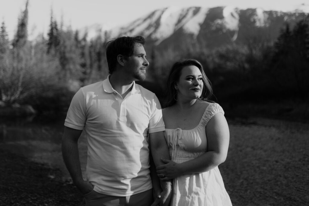 Black and white photo of couple standing in front of mountain during engagement session in Eagle RIver, Alaska