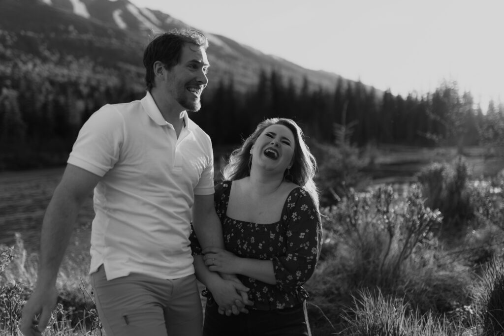 Couple with mountains behind them during golden hour laughing by river in Eagle River, Alaska