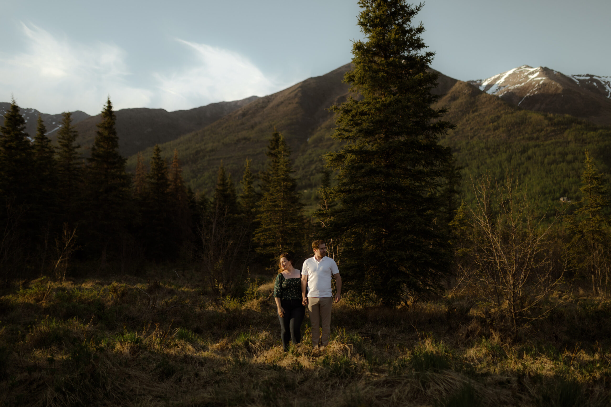 Couple standing with mountains behind them during golden hour in Eagle River, Alaska