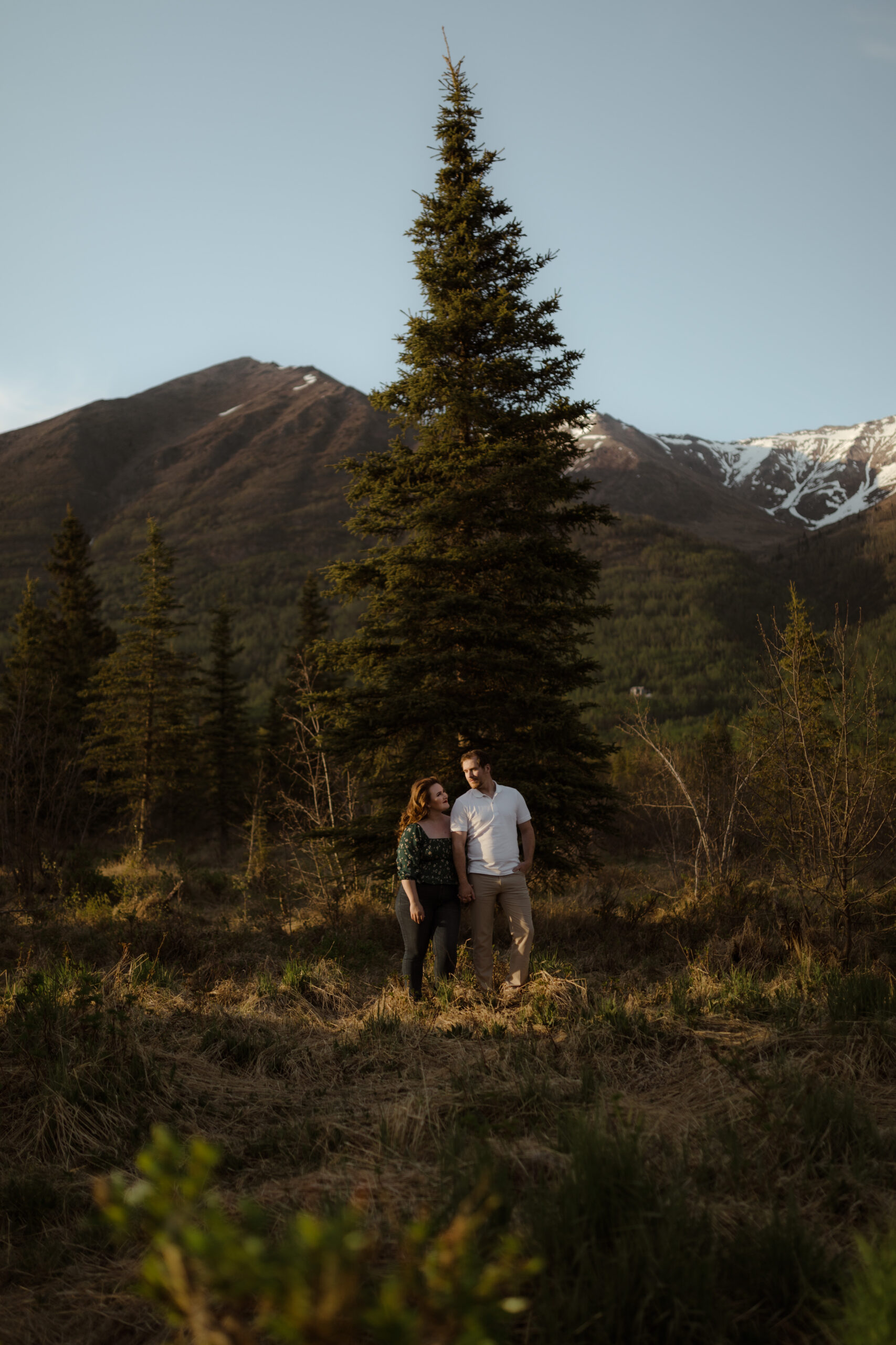 Couple standing with mountains behind them during golden hour in Eagle River, Alaska