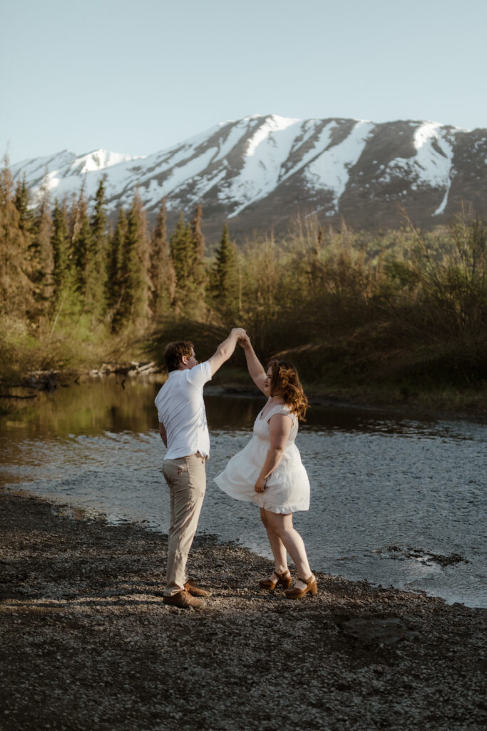 Couple dancing in front of mountain during engagement session in Eagle RIver, Alaska