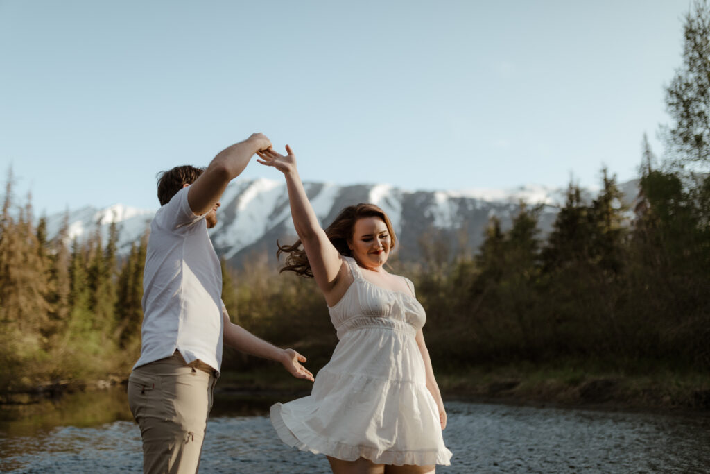 Couple dancing in front of mountain during engagement session in Eagle RIver, Alaska