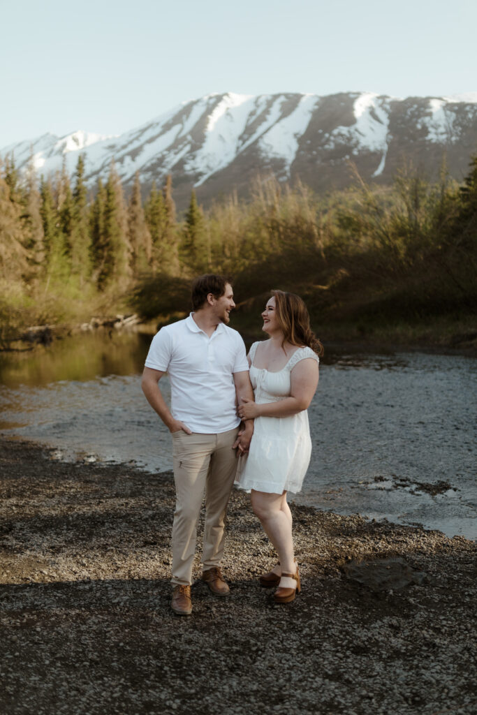 Couple standing in front of mountain during engagement session in Eagle RIver, Alaska