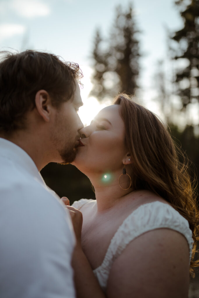 Man in a polo shirt and woman in white dress embracing with sun backlighting her in Eagle River, Alaska