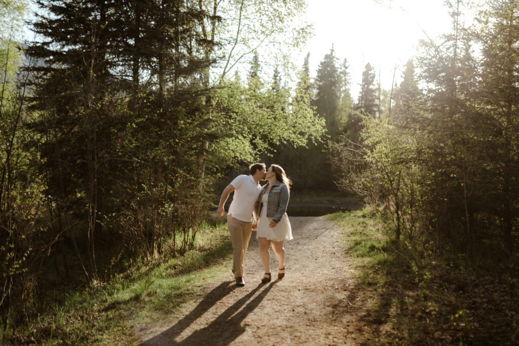 Man in a polo shirt and woman in white dress walking with sun backlighting her in Eagle River, Alaska