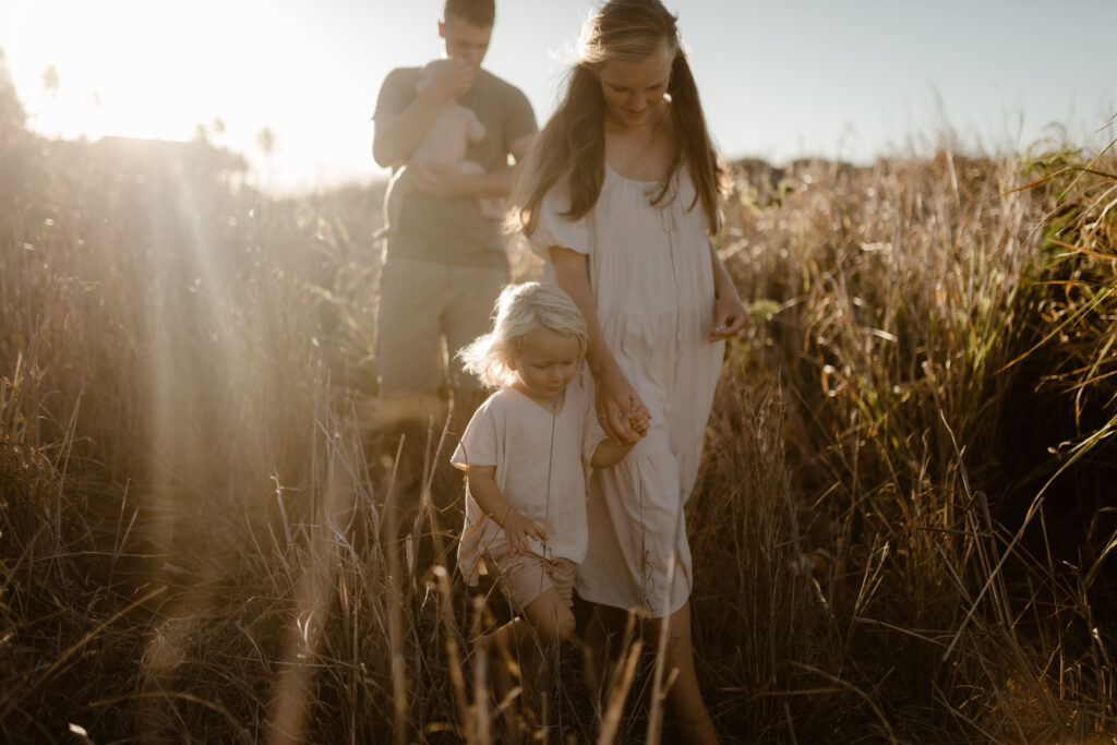 Family walking in grass at golden hour in Maui Hawaii