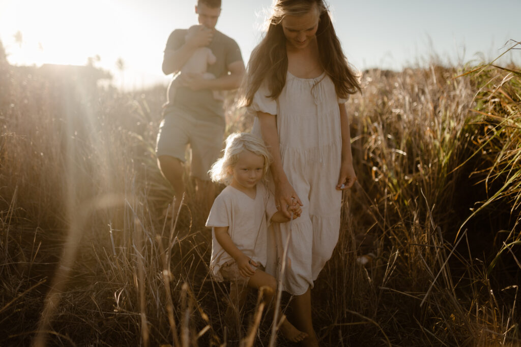 Family walking in grass at golden hour in Maui Hawaii