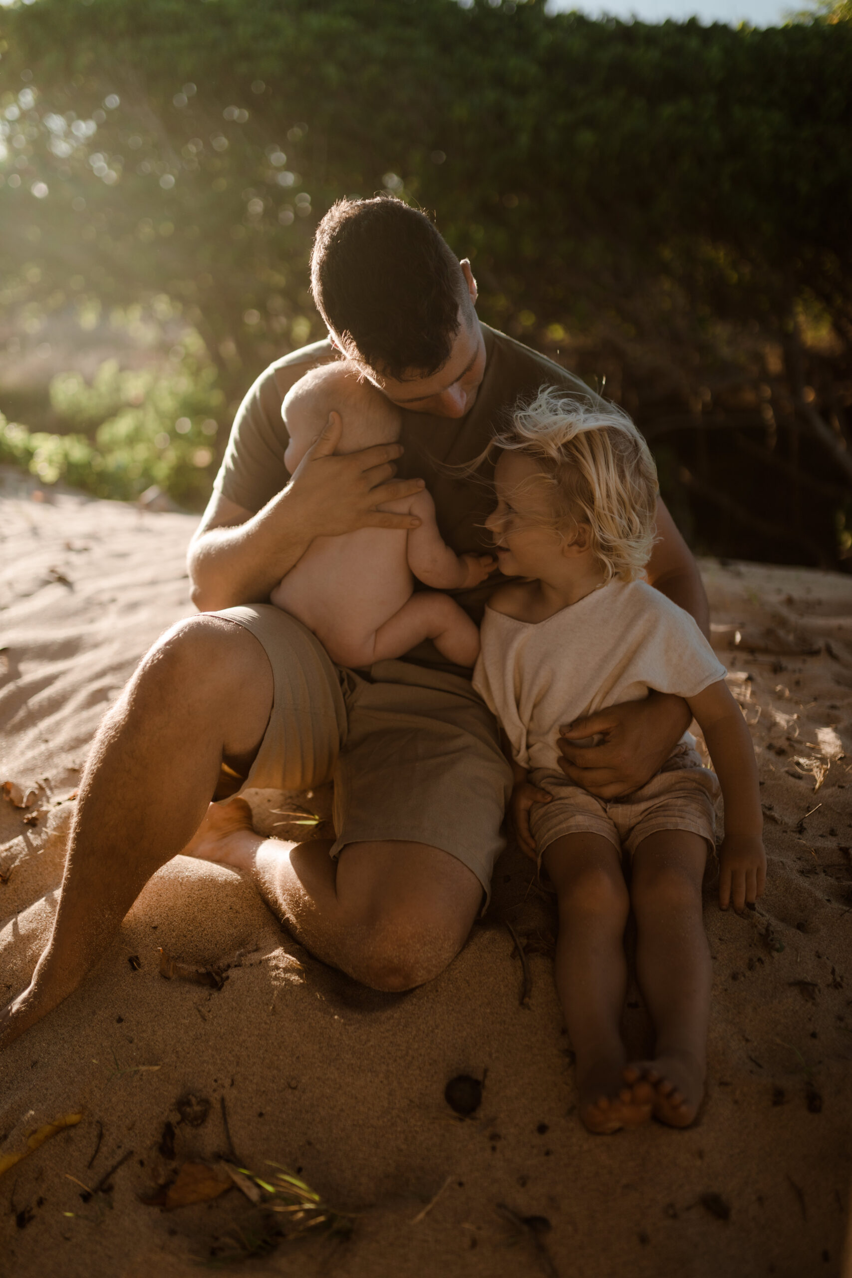 Father embracing son and infant at golden hour in Maui Hawaii