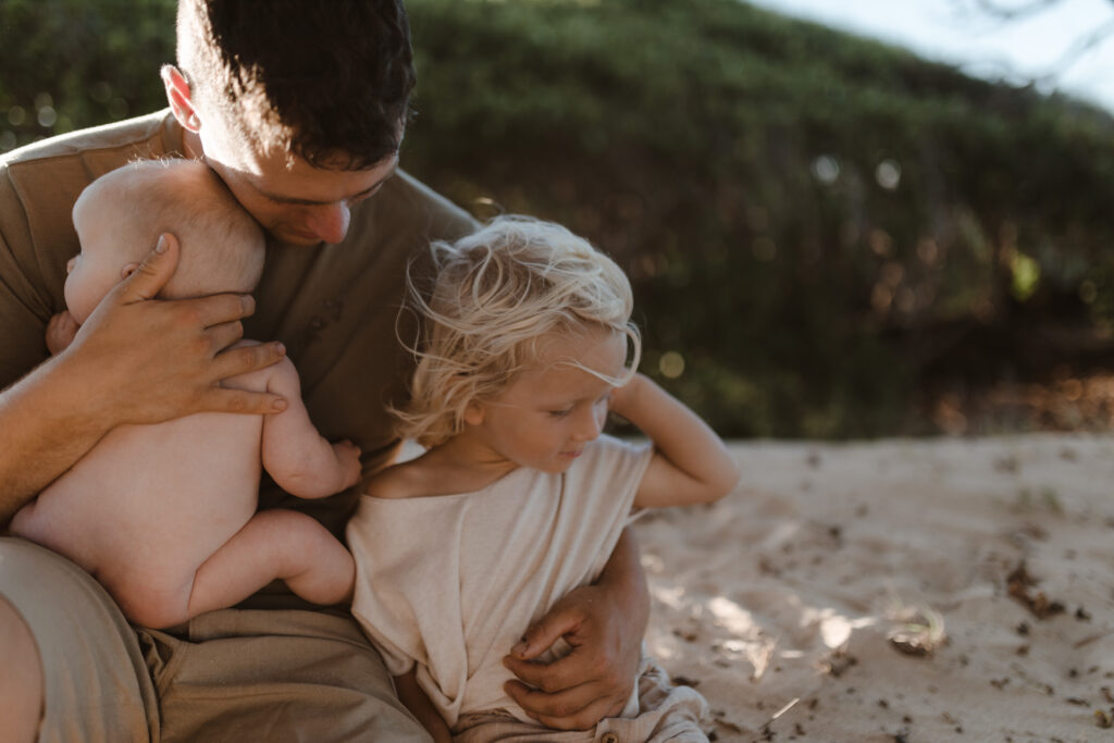 Father embracing son and infant at golden hour in Maui Hawaii