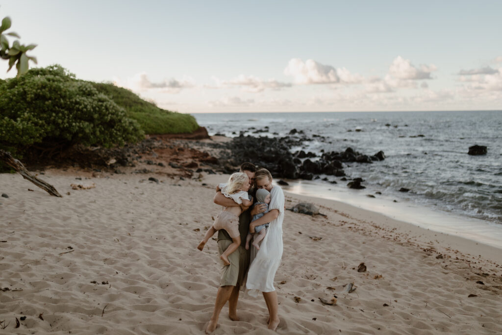 Family embracing on the beach at golden hour in Maui Hawaii