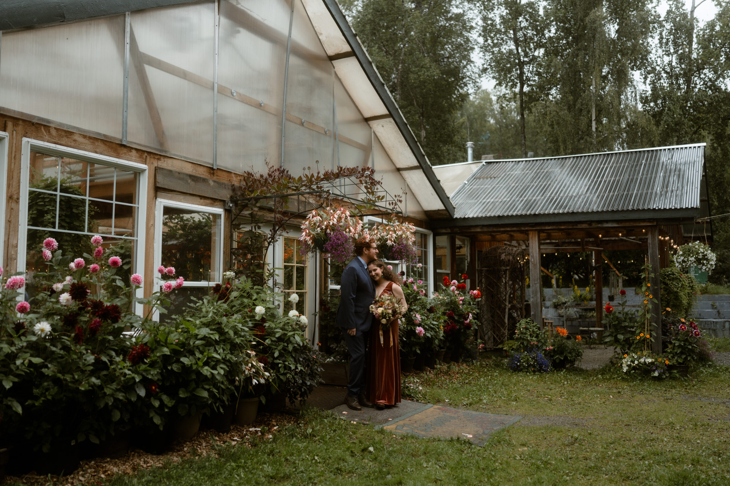 Bride and groom standing in front of Forget Me Not Nursery in Girdwood, Alaska