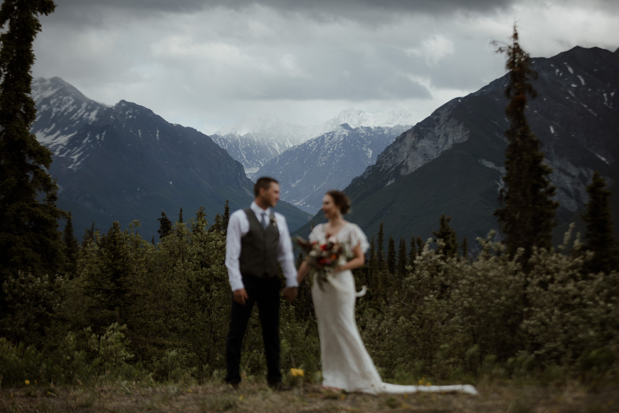 Bride and groom standing in front of mountains at Majestic Valley Wilderness Lodge in Glacier View, Alaska